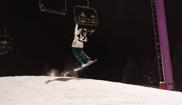 Skier hitting a jump on Purple Daze Terrain Park at Night