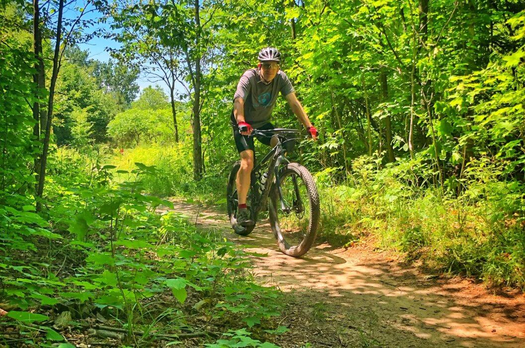 A gentleman riding his bike on a path at Glacial Hills Natural Pathway